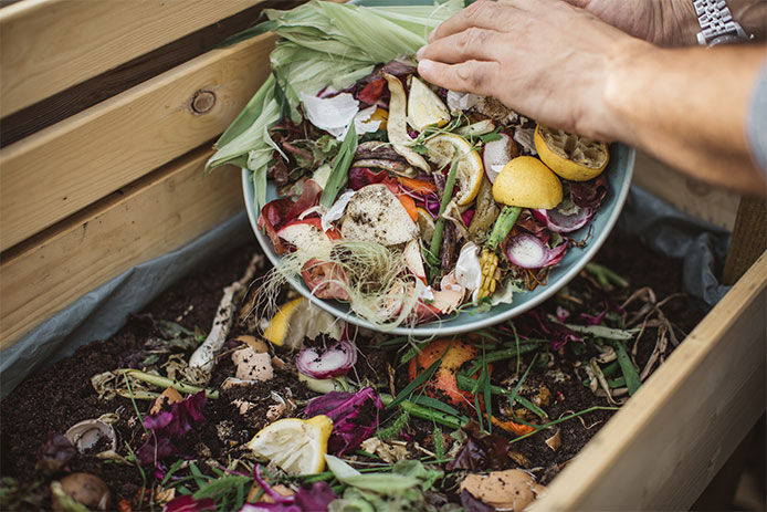 Woman putting kitchen scraps into her compost