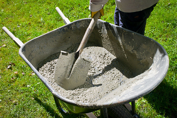 A person mixing concrete in a wheel barrow