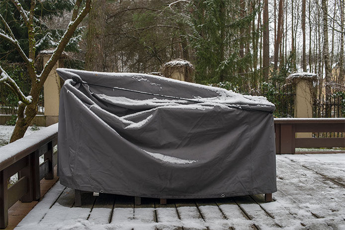 Covered patio furniture sitting on a snowy deck