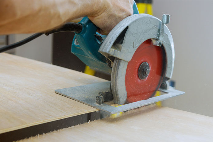 Carpenter cuts plywood on a electric circular saw