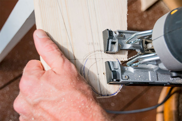 Young man carpenter builder working with electric jigsaw and wood.hobby concept.DIY acronym cut out in OSB panel with electric jigsaw.Woodworker cutting a piece of wood