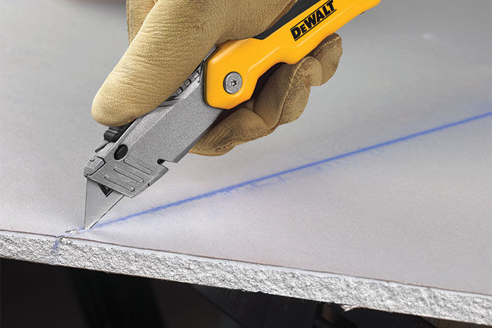 Using a utility knife to cut a piece of drywall