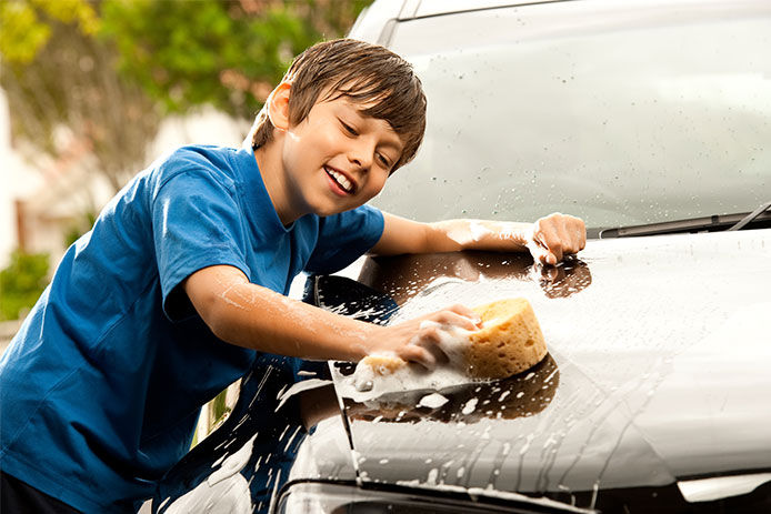 Cute boy washing a car on a hot summers day.