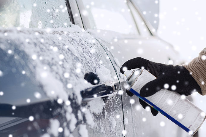 Person spraying deicer on their car door handle