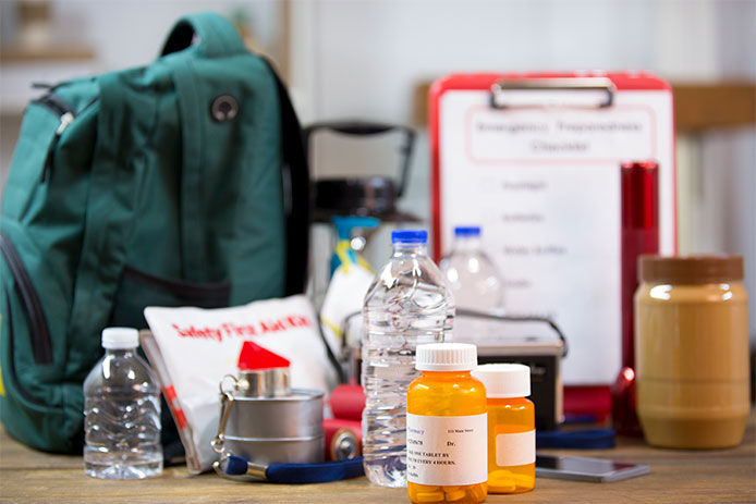 Supplies on a table in case of an emergency like: medications, water bottles, flashlight, and batteries