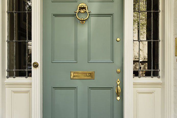 Front residence entrance with a classic design. The door has a large brass knocker and mail slot. Horizontal shot.