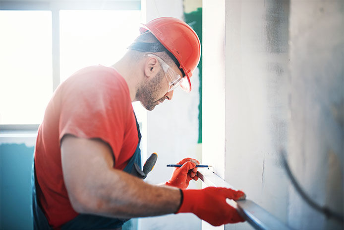 A construction man using a level to mark off spots on the wall for construction