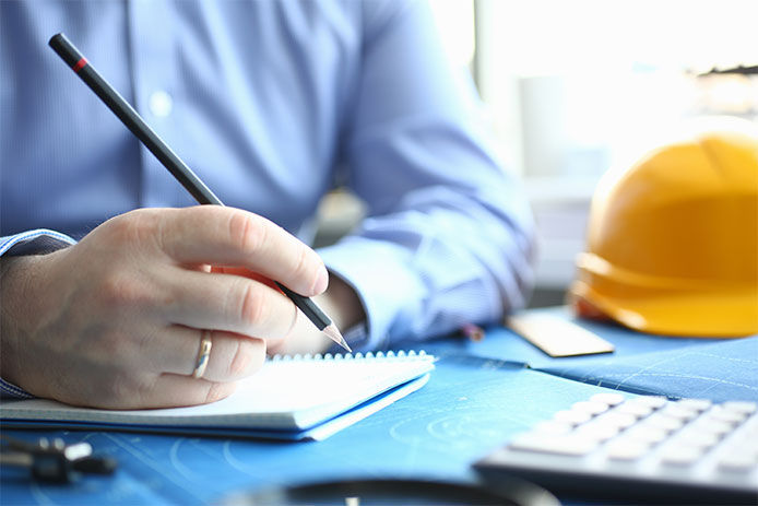 Man sitting at desk with a penchil and paper working on a construction estimate 