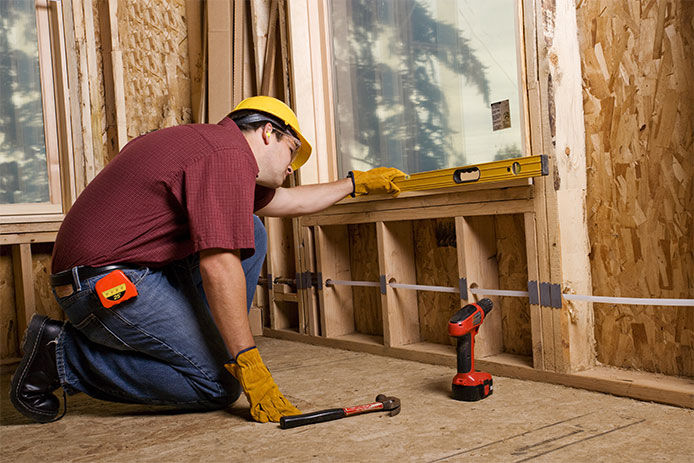 A professional construction worker installing the frame around a new window 