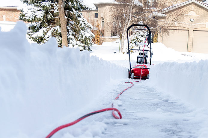 Clearing snow from a driveway using a electric snow blower after a snowstorm
