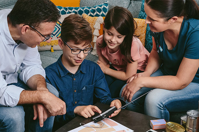 Family gathered around in a circle listening to the weather on a portable radio