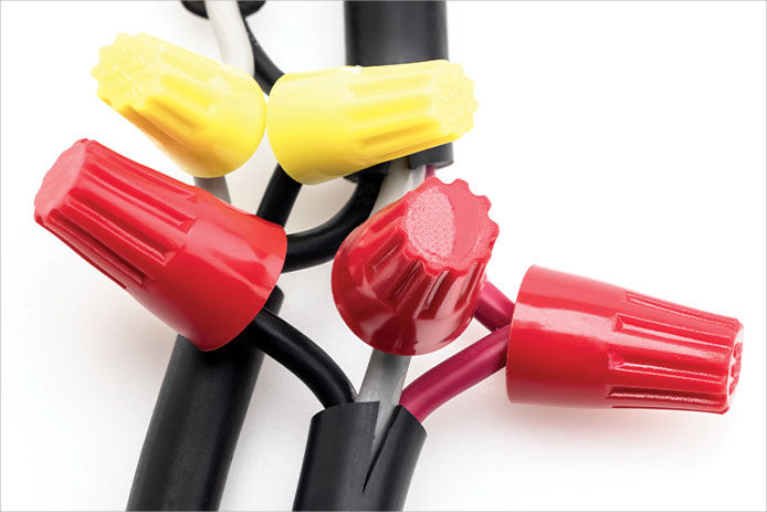 A close up of black electrical wire with red and yellow wing nuts 