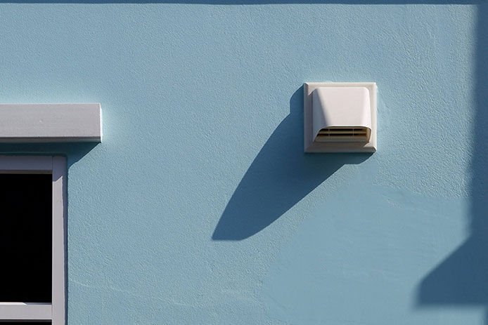 Showing a white vent on the outside of a blue house