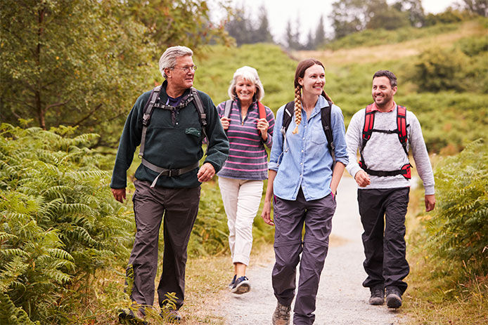 A family of four grown adults mother, father, daughter, and son, walking on a hiking trail wearing tick proof clothing. 