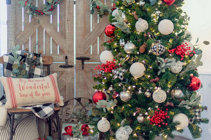 Farmhouse Christmas tree decorations with wood barn doors in the back and a burlap couch pillow