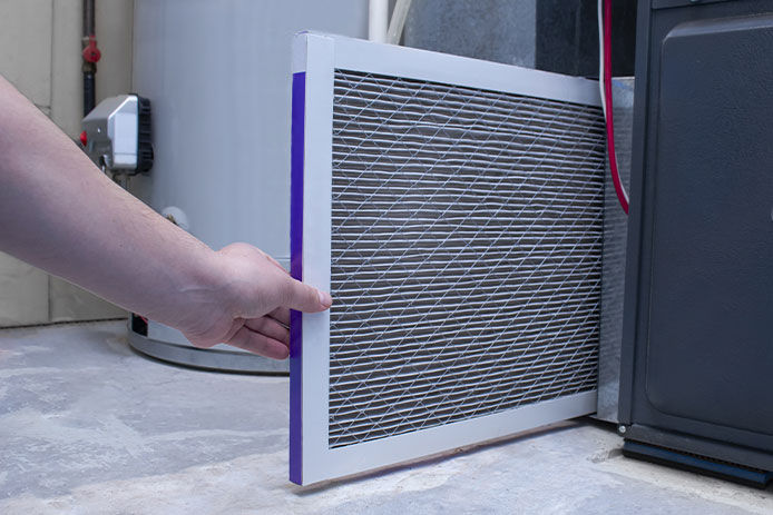A person pulling out a furnace filter