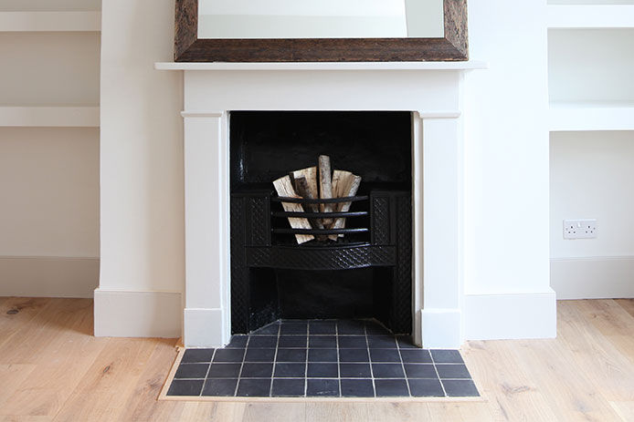 White living room fireplace with logs of wood ready to be burned