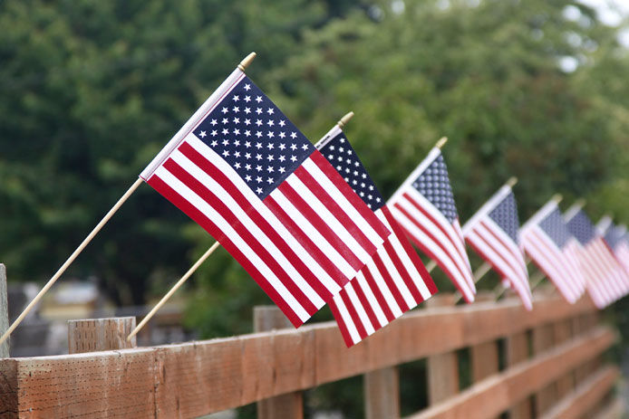 Small handheld flags stuck into a wooden fence