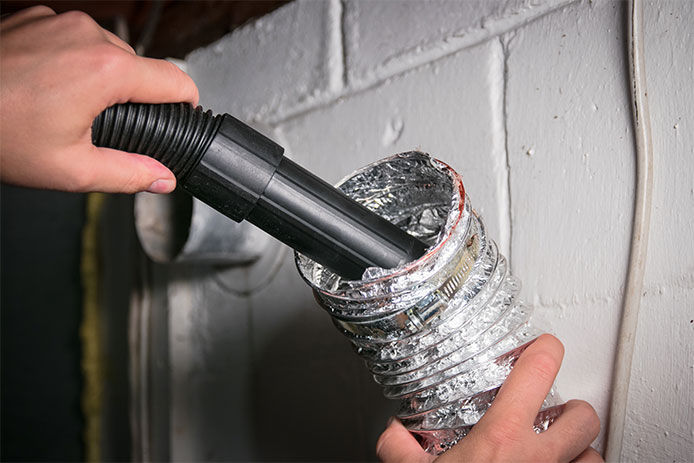 Using a vacuum hose to clean the inside of a flexible dryer duct
