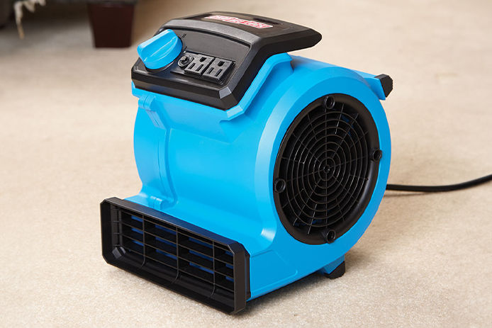A close up of a Channellock blower fan being used to dry carpet in a bedroom 