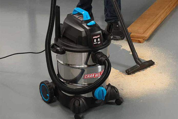 Close up of a Channellock wet/dry vacuum cleaning up saw dust on a gray garage floor
