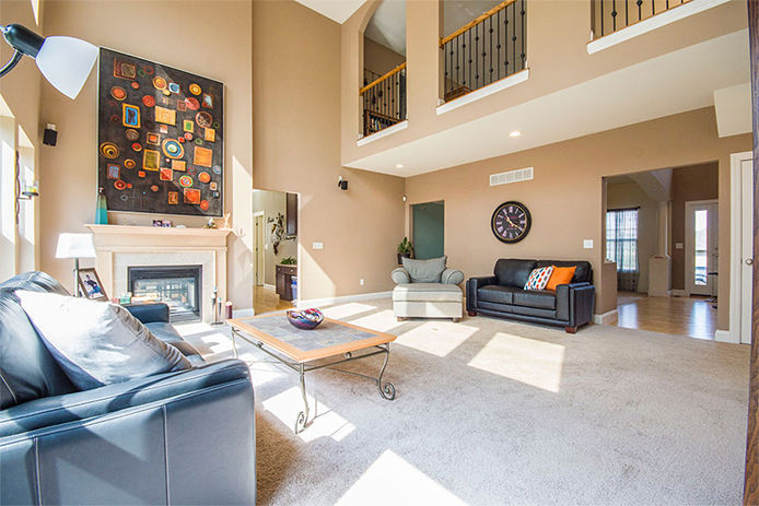 A bright luxury living room with high ceilings, banisters and art hanging from the walls 