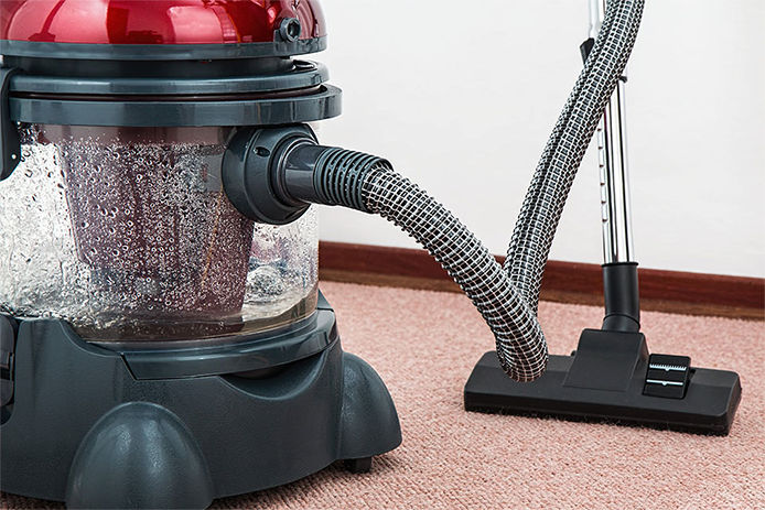 Vacumm cleaner is used to clean a carpet surface while doing houshold chores