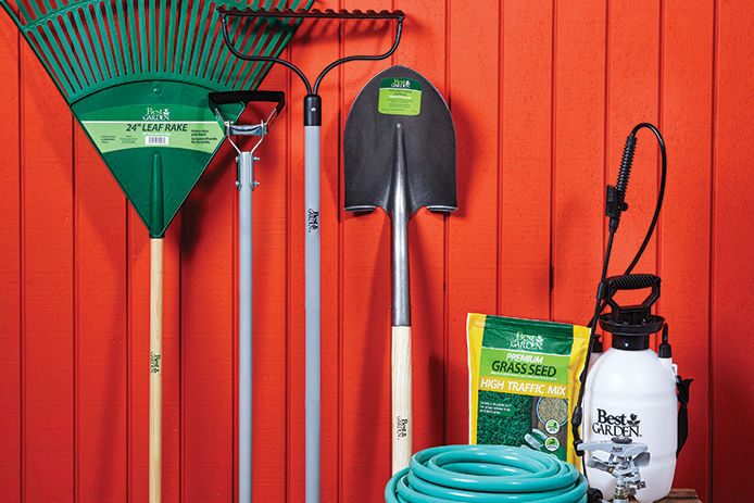 Garden tools all lined up against a red wooden tool shed