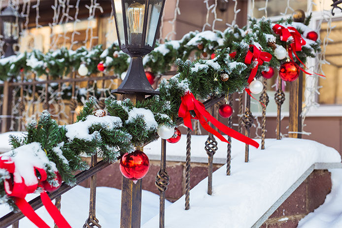 A winter garland twisted around a hand railing outside with snow on it