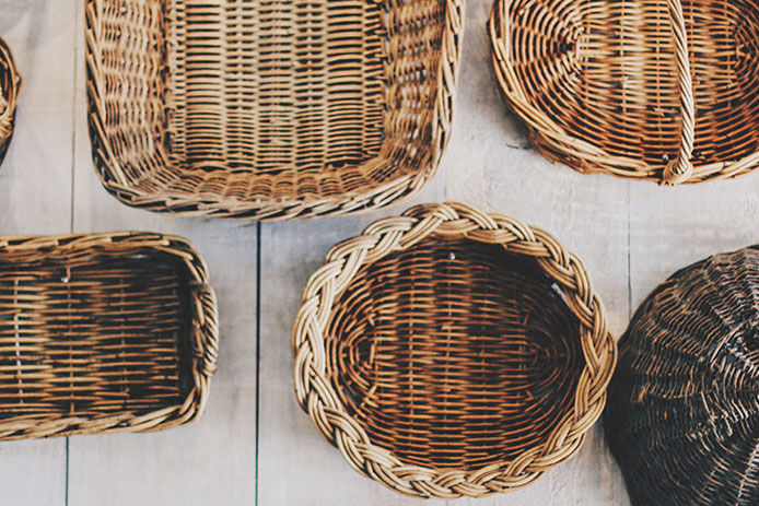 Multiple handmade woven baskets sitting on a white wooden floor