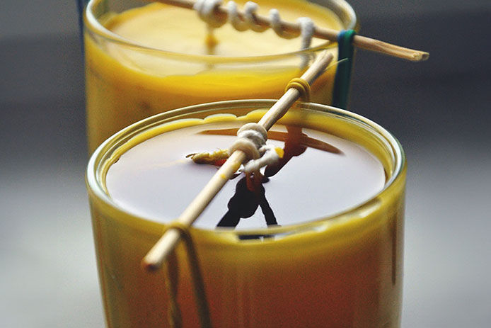A close up of two homemade candles being made with beeswax