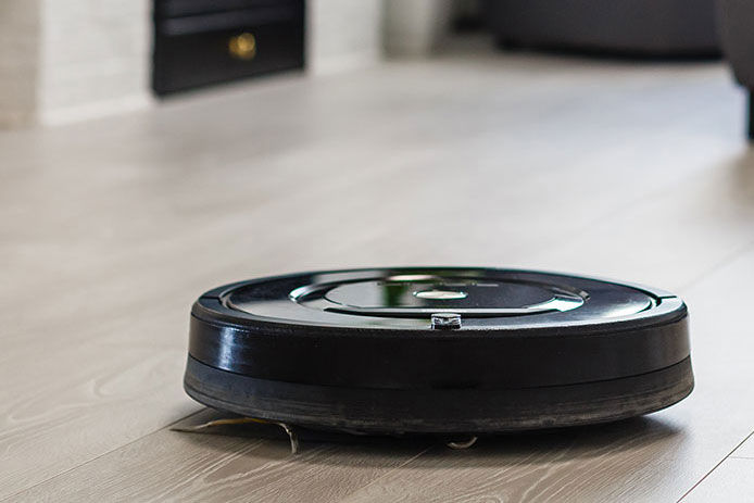 Robotic vacuum cleaner on laminate wood floor in living room
