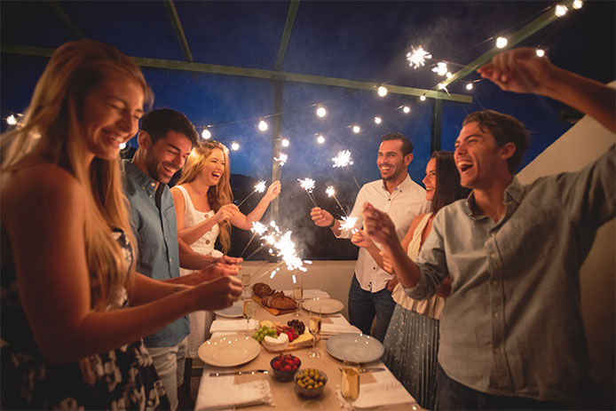 A group of friends having a celebratory dinner with sparklers 