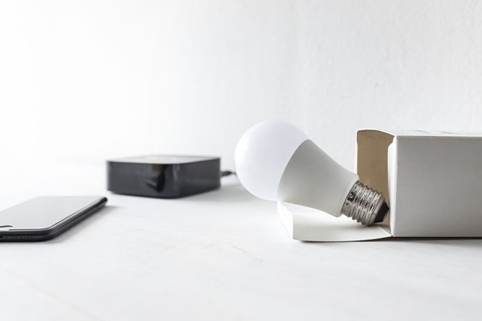 Unboxing smart lightbulb with a smart phone and hub in the background