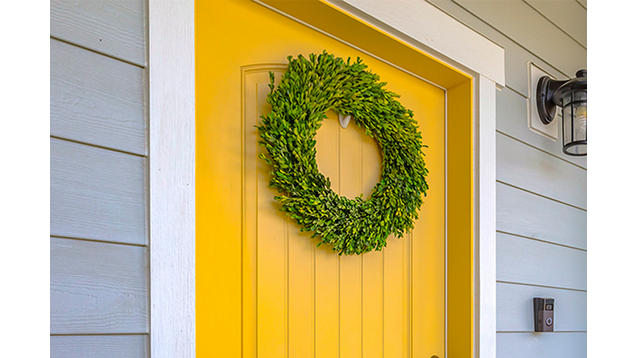 Front door painted a bright yellow with a decorative wreath