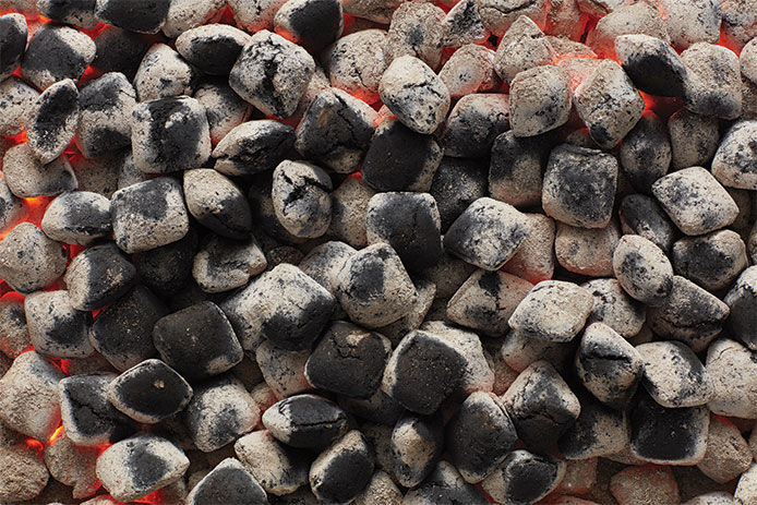 A close up image of black and gray burning charcoal 
