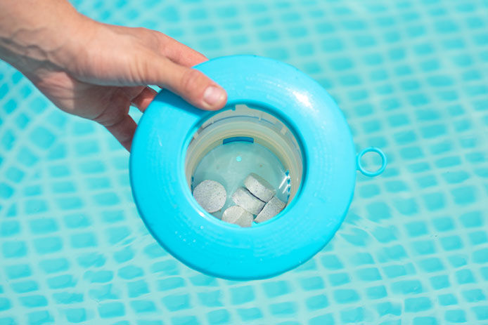 Person holding a chlorine dispenser with chlorine tablets in it