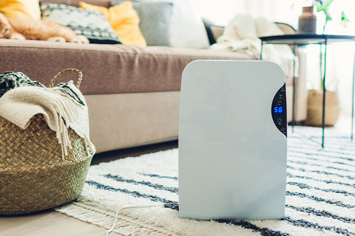 Humidifier sitting on a carpet in a living room with a couch and coffee table in the background