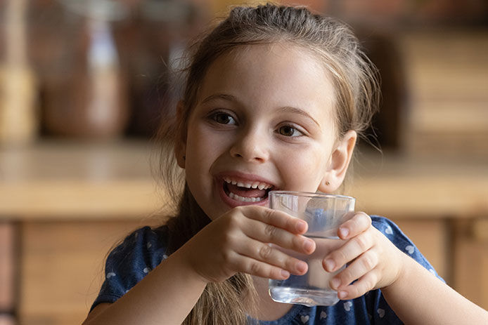 Little girl smiling holding a glass of water
