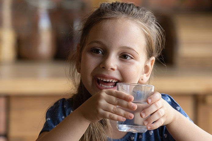 Little girl smiling holding a glass of water