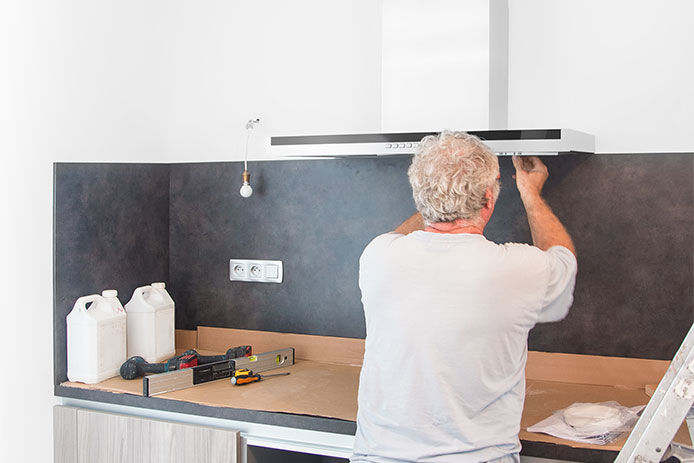 Man is installing new range hood and getting everything connected