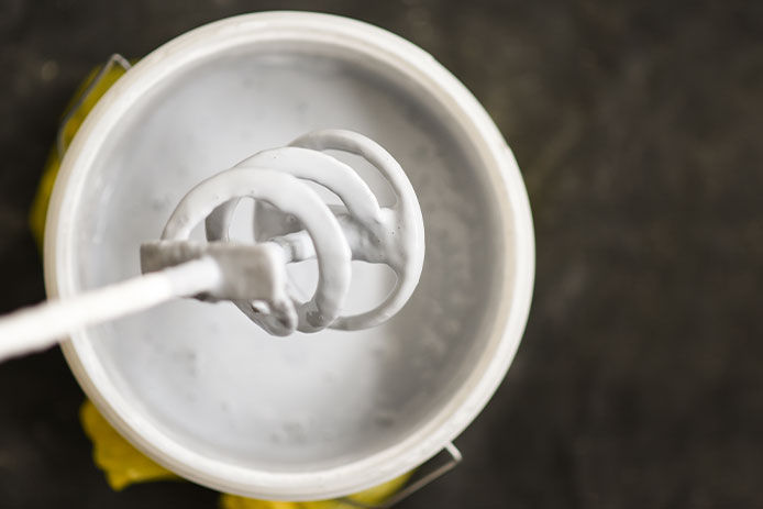 Paddle mixer over the bucket with white paint for wall, DIY tools and accessory, workflow close up, banner 