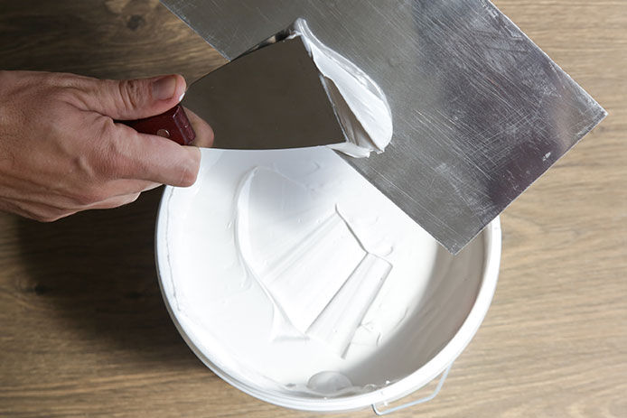 Person putting joint compound onto a putty knife