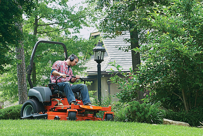 Man on a riding zero-turn lawn mover wearing over the ear protection