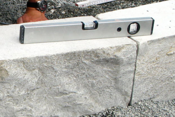 Pavers stones being laid down on a pile of bricks with a level on top to ensure they are even