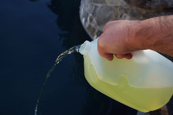 Pouring liquid chlorine into a pool