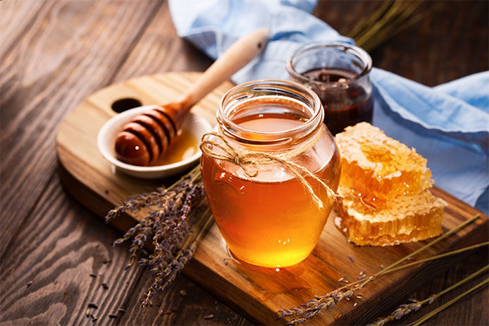 A jar of honey and a honeycomb on a wooden table 