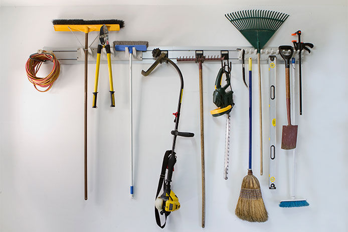 Long handled garden tools hanging from garage wall