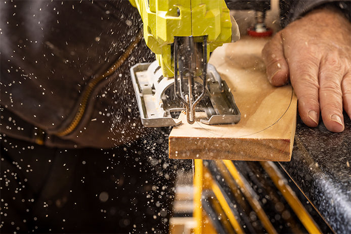 A jigsaw being used to cut a curve on a work piece of soft pine.