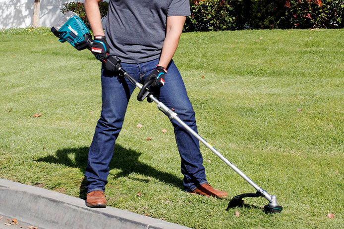 Makita string trimmer attachment being used to trim down grass